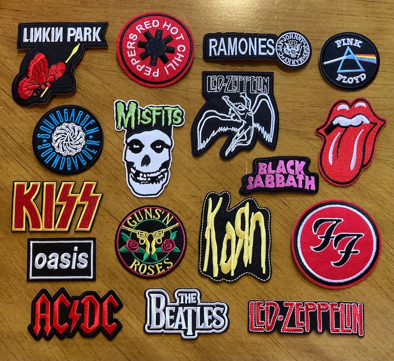 May include: A collection of 16 embroidered iron-on patches featuring various rock band logos, including Linkin Park, Red Hot Chili Peppers, Ramones, Led Zeppelin, Misfits, Black Sabbath, Kiss, Guns N' Roses, Oasis, AC/DC, The Beatles, and Foo Fighters.