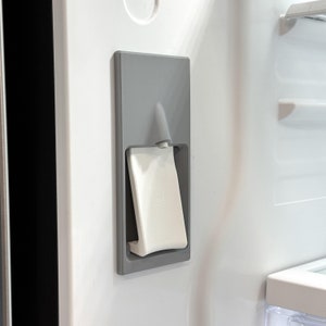 May include: A grey refrigerator door with a white water dispenser button. The button has a water drop icon.
