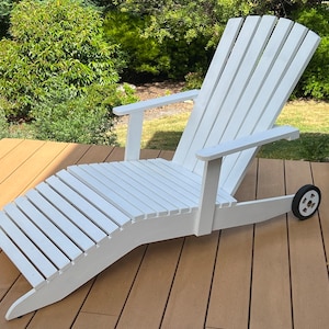 K&ouml;nnte beinhalten: Wei&szlig;er Adirondack-Stuhl aus Holz mit Fu&szlig;st&uuml;tze und einem Rad auf einer Seite. Der Stuhl steht auf einem Holzdeck.