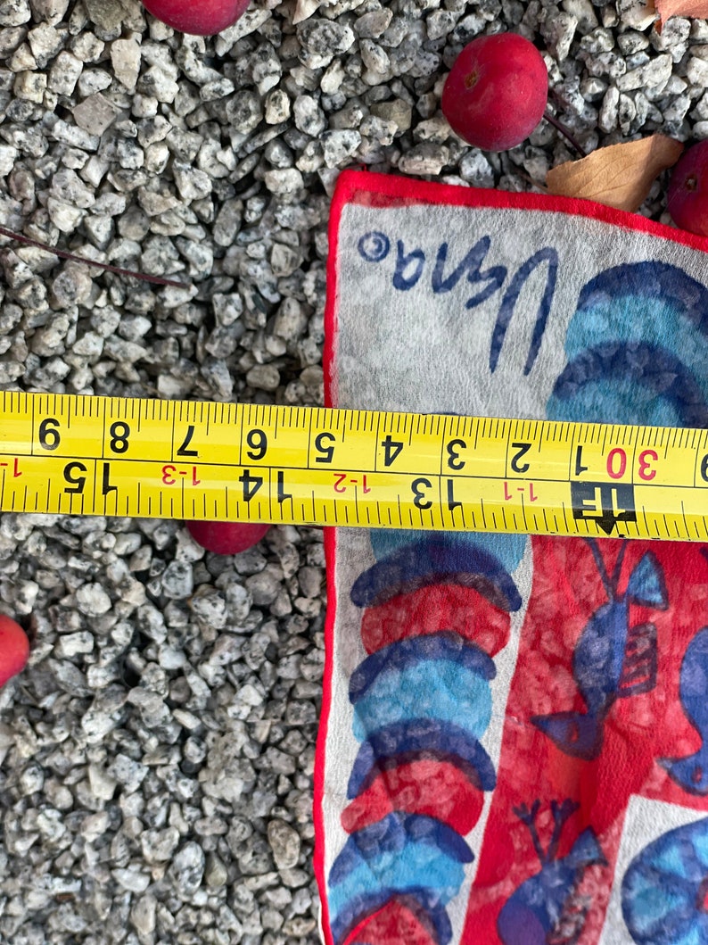 May include: A white cotton handkerchief with a red, blue, and white design of lobsters and seashells. The handkerchief is 15 inches long and 8 inches wide. The text "Vana" is printed in the top right corner.