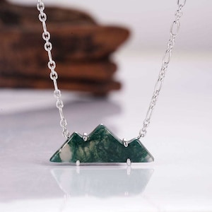 May include: A silver chain necklace with a green agate mountain pendant. The pendant is made of a natural stone with a unique pattern.