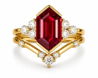 May include: A gold ring set featuring a central hexagonal-cut deep red gemstone. The band is accented with small, round, clear white stones arranged in clusters on the sides and along a V-shaped contour band that sits beneath the main setting.