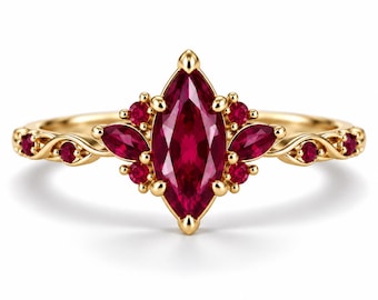 May include: A gold ring featuring a central marquise-cut red gemstone surrounded by smaller round and marquise-cut red stones. The band has a delicate, twisted metal design with additional small red stones set along the sides.
