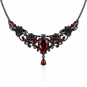 May include: Black gothic-style necklace featuring a large oval red gemstone pendant and smaller red accents. The necklace has a floral design with roses and a teardrop-shaped gemstone. The chain is black.