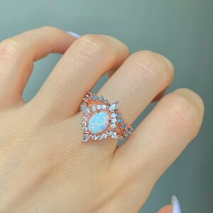 May include: A rose gold ring with a large oval opal surrounded by smaller clear and blue stones.