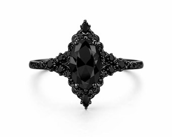 May include: A black engagement ring with an oval-cut center stone and a decorative setting. The ring features a dark, ornate design with smaller black stones surrounding the main gem. The band is also black.