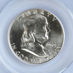 May include: A silver half dollar coin with the image of Benjamin Franklin on the obverse. The coin has the inscription "LIBERTY" above Franklin's head and "IN GOD WE TRUST" below. The date "1953" is inscribed on the right side of the coin.