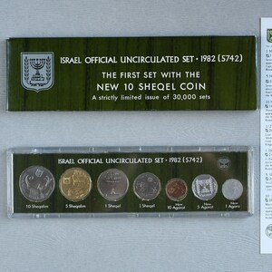 May include: A set of three ceramic mugs with a speckled, matte finish. The mugs are in shades of cream, light gray, and dark gray. Each mug has a simple, minimalist design and a rounded handle. The mugs are suitable for coffee, tea, or other beverages.