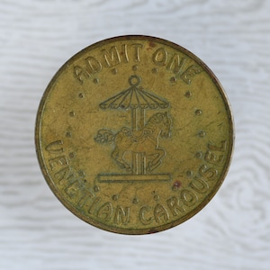 May include: A brass token with the words "ADMIT ONE VENETIAN CAROUSEL" and a depiction of a carousel horse with a canopy.