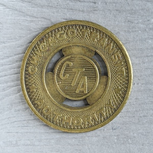 May include: A gold-colored metal token with the words "Chicago Transit Authority" and "CTA" in the center. The token has a star on the left side and a grid pattern around the edge.