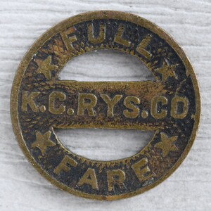 May include: A brass token with the words "Full Fare" and "K.C. Rys. Co." around a circular hole. The token has three stars on the outer edge.