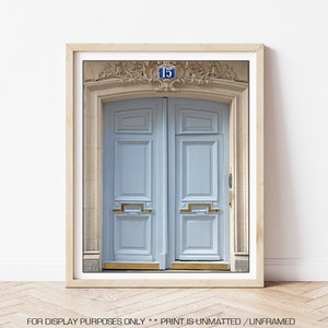 May include: A light blue double door with gold accents and a brass door handle. The door is framed by a stone archway with ornate details and a blue plaque with the number "15" on it.