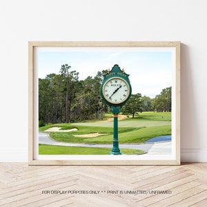 May include: A green clock with gold accents and the words "Poppy Hills" and "Rolex" on the face. The clock is on a green pole and is set against a backdrop of a golf course with green grass and trees.