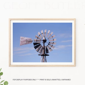 May include: A vintage windmill with a faded sign that reads "Die Aermotor Co." against a bright blue sky.