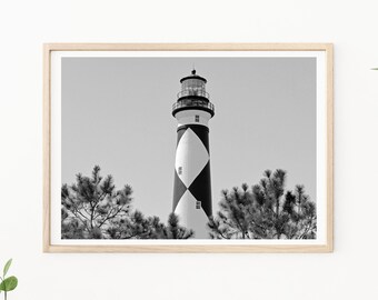 May include: Black and white photograph of a lighthouse with a black and white diamond pattern. The lighthouse is surrounded by trees.