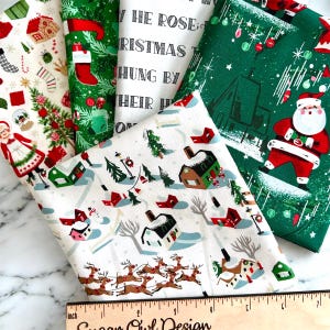 May include: A collection of Christmas-themed fabric pieces with various patterns. Designs include Santa Claus, reindeer, snow-covered houses, Christmas trees, and stockings. The fabrics are in shades of green, white, and red, with a ruler at the bottom.