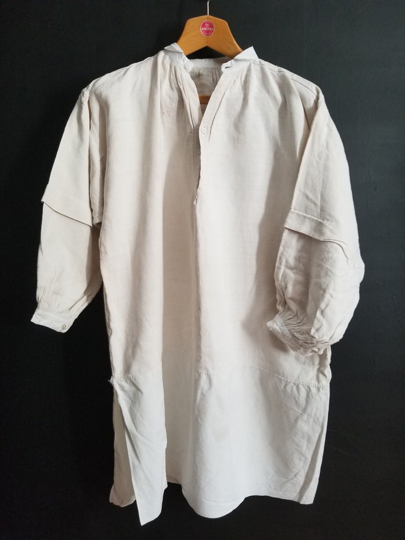 May include: A long-sleeved, off-white linen shirt with a button-up front and gathered cuffs. The shirt has a simple, classic design.