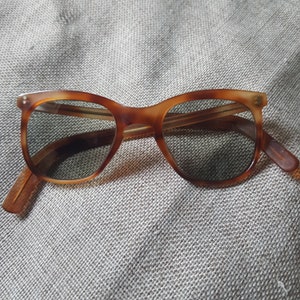 May include: Tortoise shell sunglasses with brown frames and dark lenses.