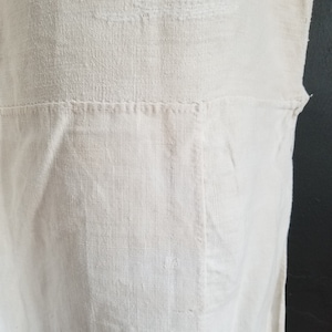 May include: A white linen fabric with a subtle texture. The fabric has a seam running horizontally across the middle.
