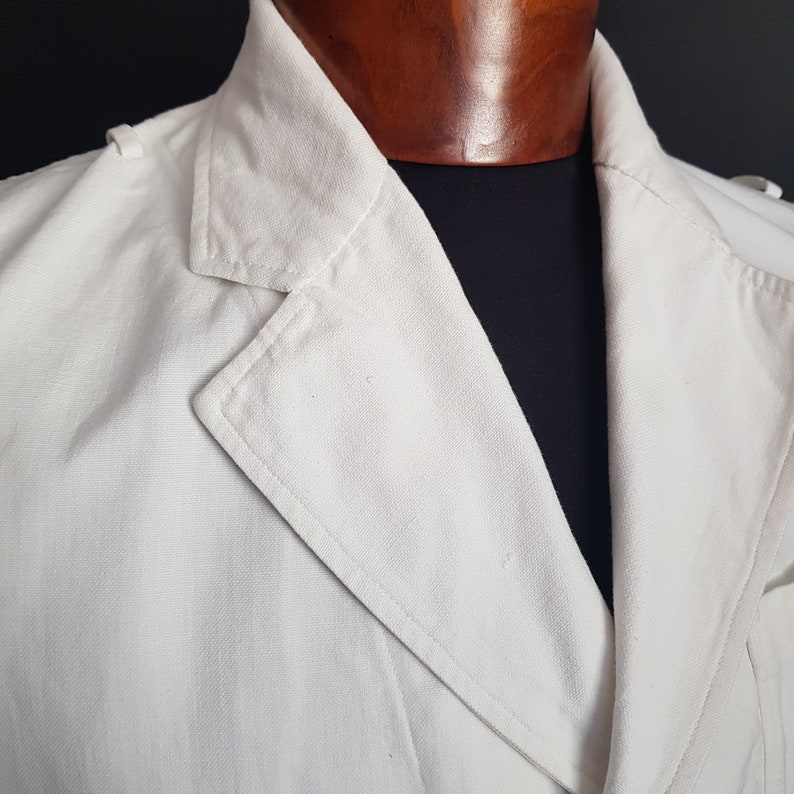 May include: A white linen jacket with a double-breasted closure and a large collar.