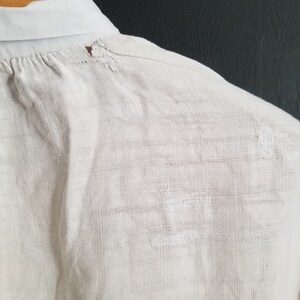 May include: A white linen shirt with a small hole near the collar.