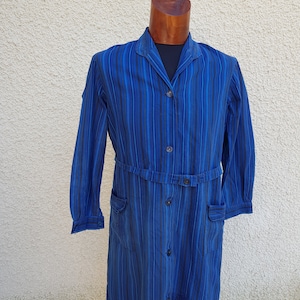 May include: A long-sleeved blue and black striped workwear dress with a button-up front, a belt, and two pockets.