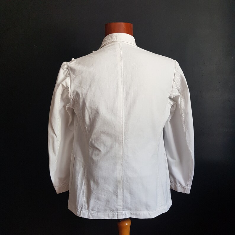 May include: A white blazer with long sleeves and a single button closure. The blazer has a classic design and is made of a lightweight fabric.