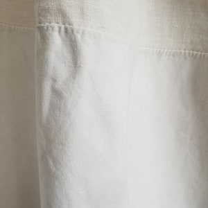May include: White linen fabric with a textured weave. The fabric is sewn together with a seam.