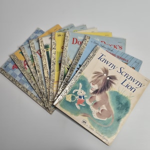 May include: A collection of ten vintage Little Golden Books arranged in a fan shape. Each book features a distinct illustrated cover and a signature gold-patterned spine. The top book is titled Tawny Scrawny Lion and depicts a lion and a rabbit.