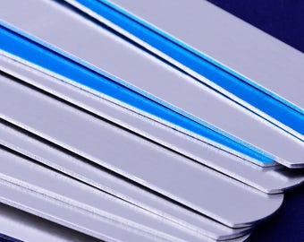 May include: A stack of silver-colored metal rulers with a blue stripe along the edge.
