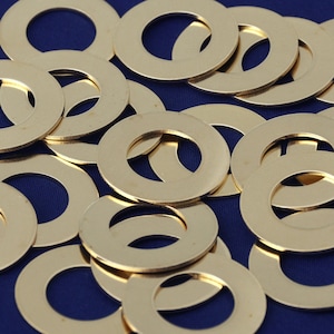 Puede incluir: Primer plano de un montón de arandelas de metal de color dorado. Las arandelas están dispuestas en un patrón aleatorio sobre una superficie azul.