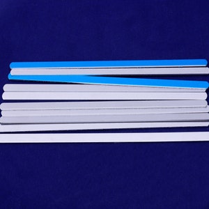 Puede incluir: Una pila de tiras de plástico grises y azules sobre un fondo azul oscuro. Las tiras son todas del mismo tamaño y forma, y están dispuestas en una pila ordenada.