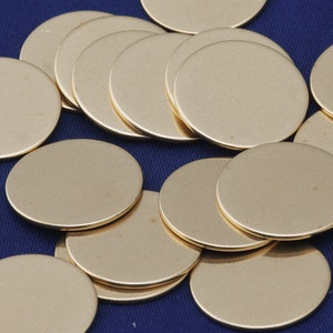 Puede incluir: Una pila de discos de metal redondos de color dorado. Los discos son lisos y brillantes, y están dispuestos en un patrón aleatorio.
