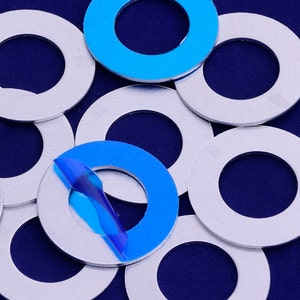 Op de afbeelding: Een groep zilveren metalen ringen met een blauwe ring op een van de ringen.