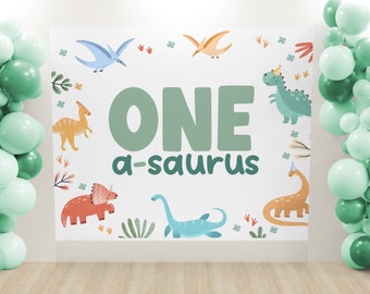 Pode incluir: Um fundo branco com as palavras "ONE a-saurus" em texto verde. O fundo é decorado com dinossauros, flores e folhas. Há balões verdes de cada lado do fundo.