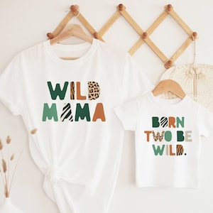 May include: Two white t-shirts with a green, orange, and brown animal print design. The larger shirt says "WILD MAMA" and the smaller shirt says "BORN TO BE WILD."