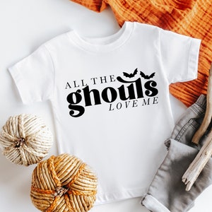 May include: White baby onesie with black text that reads "All the ghouls love me" and two black bats above the text.