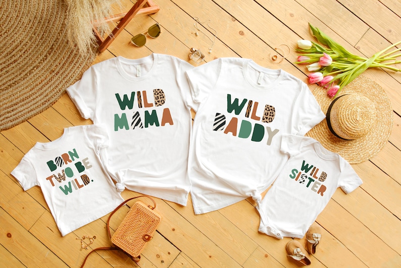 May include: A set of four white t-shirts with a jungle animal theme. The shirts feature the text "Wild Mama", "Wild Daddy", "Born to be Wild", and "Wild Sister".