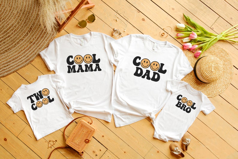 May include: Four white t-shirts with a retro design featuring smiling faces and the text "Cool Mama", "Cool Dad", "Two Cool", and "Cool Bro".