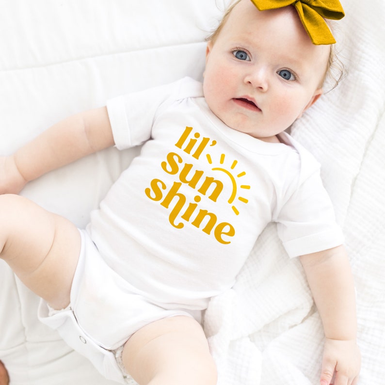 May include: A white baby onesie with a yellow graphic that says "lil' sun shine" and a yellow sun graphic.