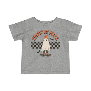 May include: A gray t-shirt with a ghost wearing a beanie and skateboarding. The text "CREEP IT REAL" is above the ghost.