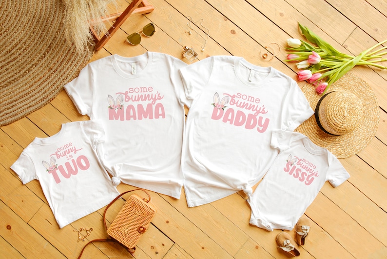 May include: Four white t-shirts with pink bunny graphics and text. The shirts say "Some Bunny is Two", "Some Bunny's Mama", "Some Bunny's Daddy", and "Some Bunny's Sissy".