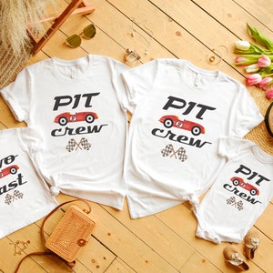 May include: Four white t-shirts with a red race car graphic and the text "PIT crew" and "two fast".