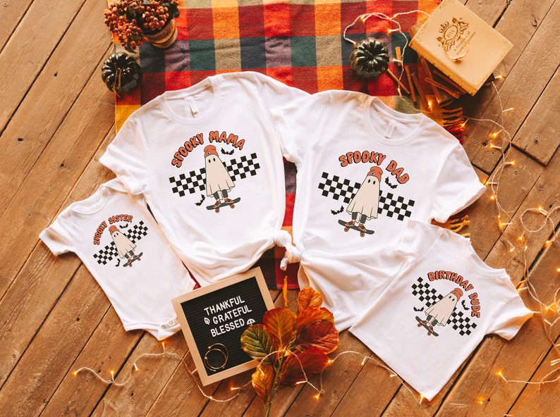 May include: Four white t-shirts with a ghost skateboarding graphic. The shirts say "Spooky Mama", "Spooky Dad", "Spooky Sister", and "Birthday Dude".