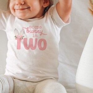 May include: A white t-shirt with a pink bunny graphic and the text "some bunny is two".