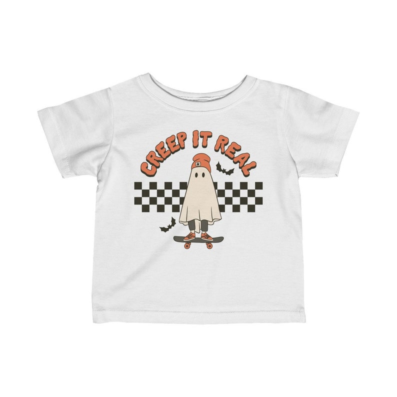 May include: White baby t-shirt with a ghost wearing a red beanie and skateboarding. The ghost is in front of a black and white checkered pattern with the text "CREEP IT REAL" above the ghost.