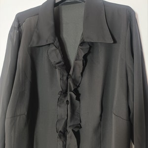 May include: A black long-sleeved blouse with a ruffled front and button closure.