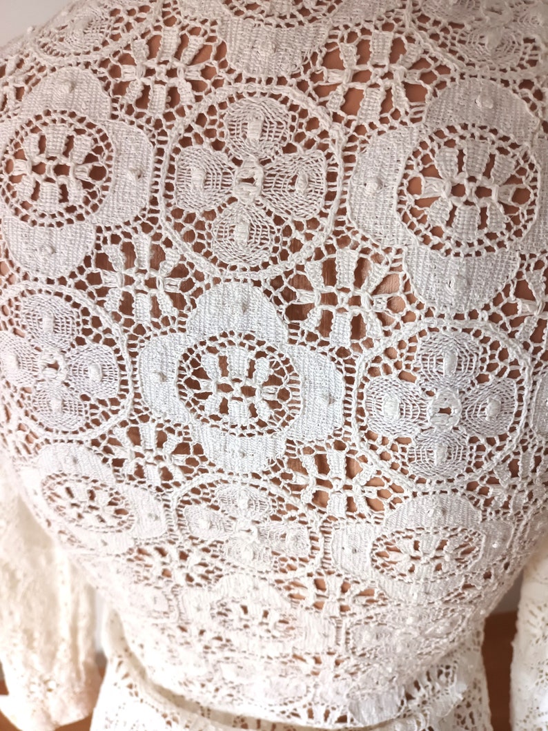 May include: White crochet fabric with a delicate floral pattern.