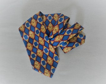 May include: A blue and gold patterned silk necktie with a diamond pattern and floral accents.