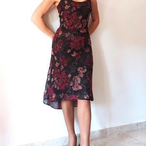 Peut inclure: Une robe midi noire &agrave; imprim&eacute; floral avec des roses rouges et roses. La robe a un corsage ajust&eacute; et une jupe fluide.